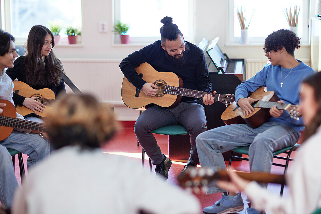 Teenagers attending guitar lesson