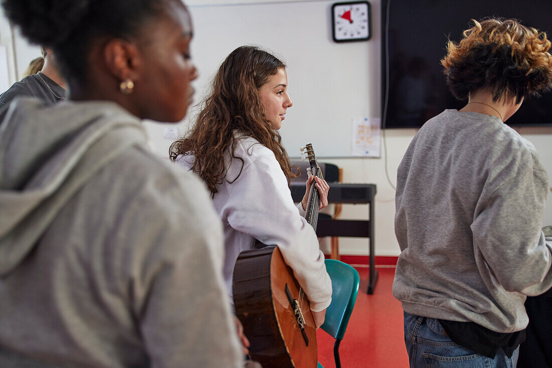 Teenagers attending guitar lesson