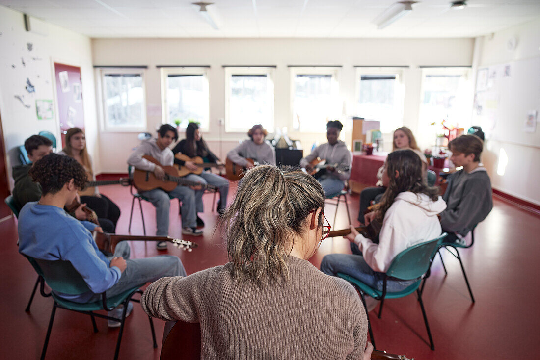 Teenagers attending guitar lesson