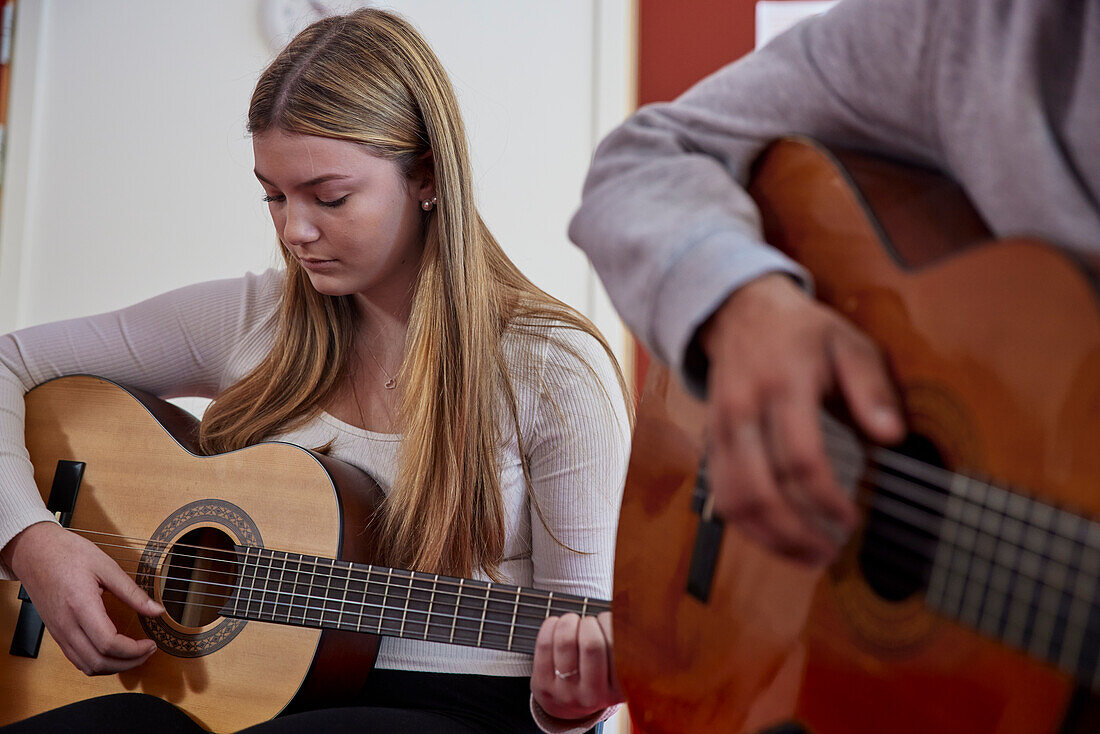 Teenager beim Gitarrenunterricht