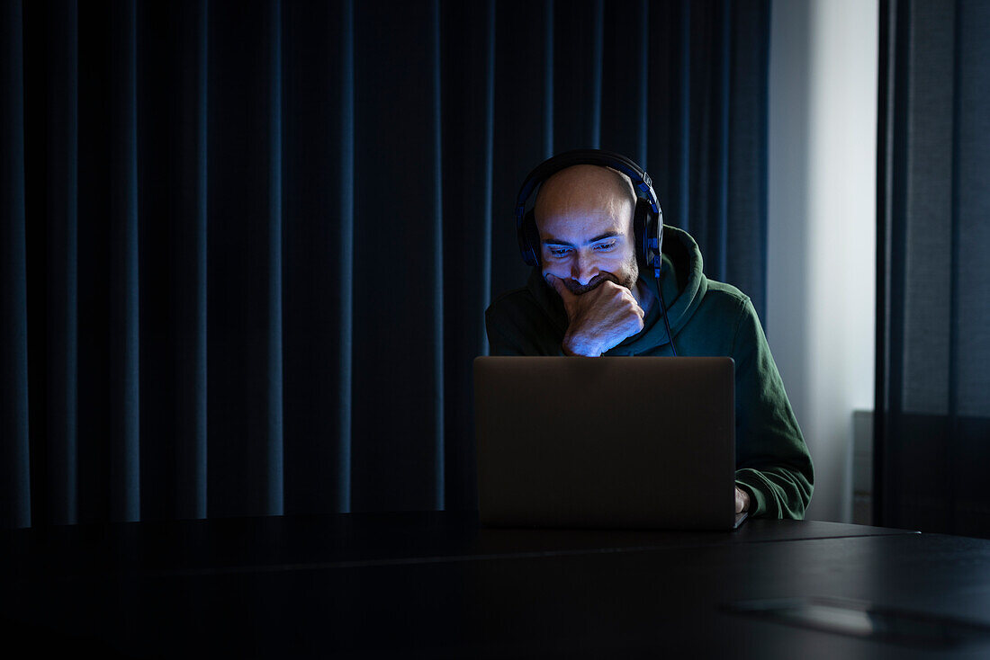 Man working on laptop in dark office