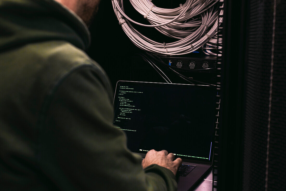 IT technician working on laptop in server room