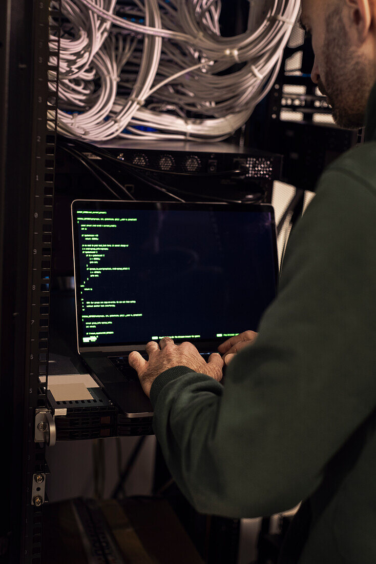 IT technician working on laptop in server room