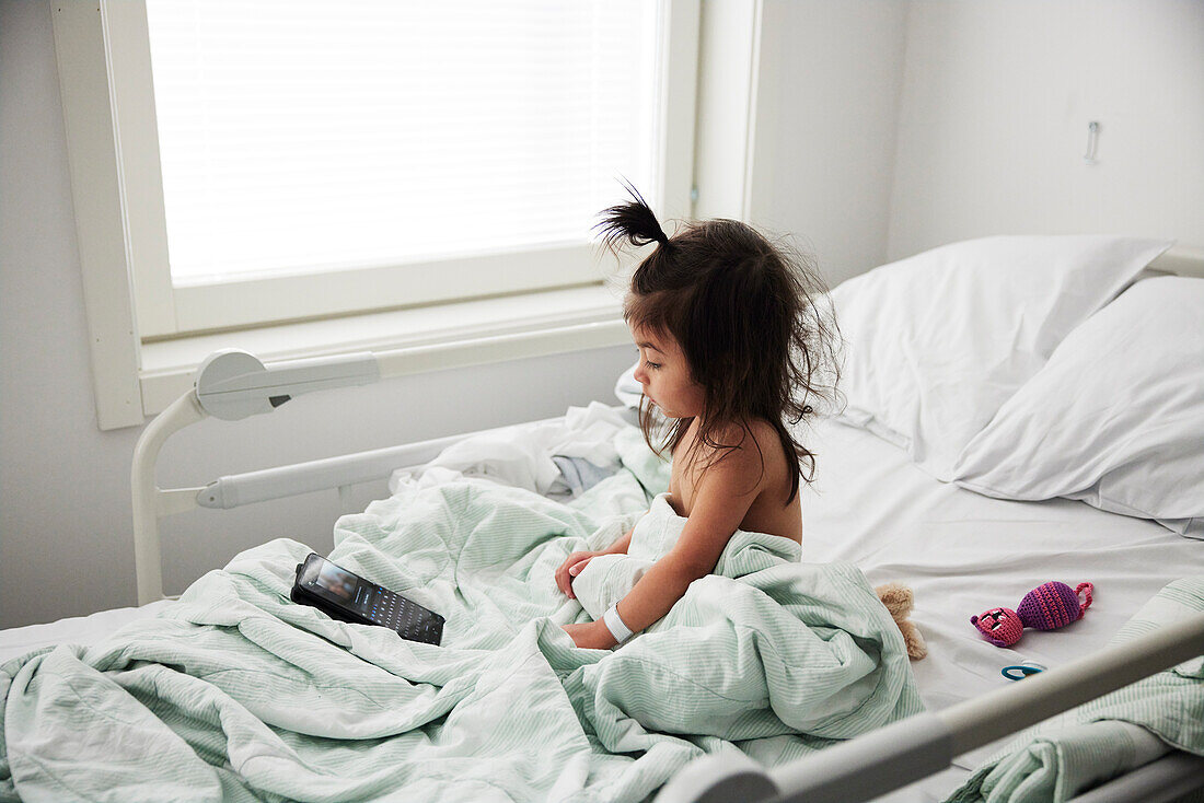 Girl using phone in hospital bed