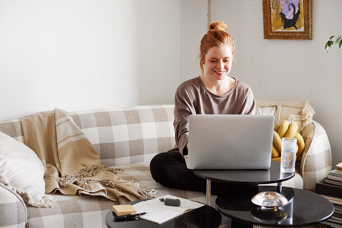 Lächelnde Frau benutzt Laptop zu Hause