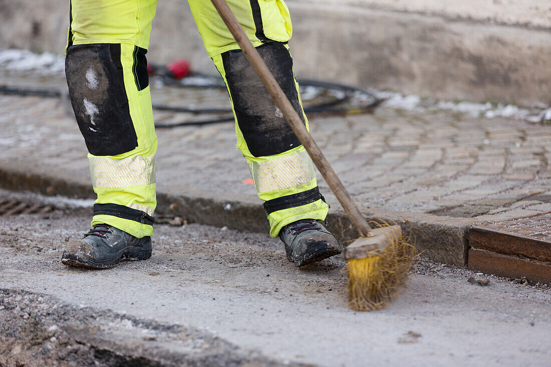 Arbeiter in reflektierender Kleidung beim Kehren der Straße