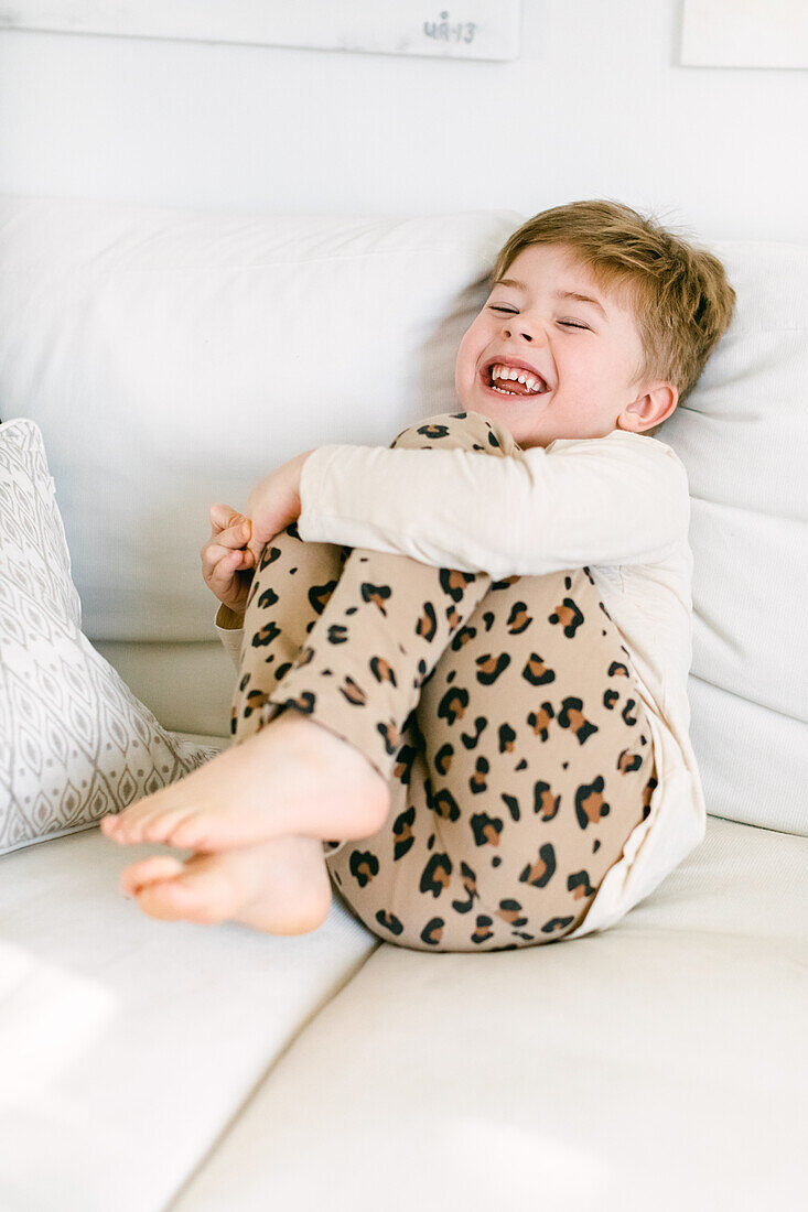 Laughing boy sitting on sofa