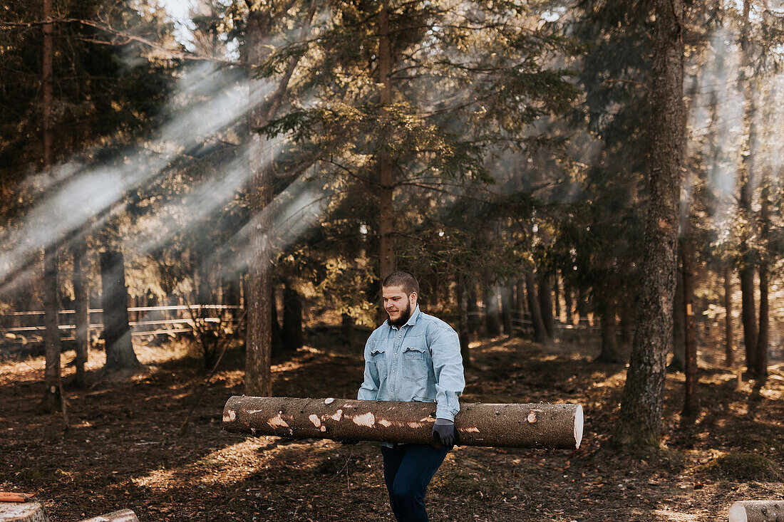 Man carrying log in forest