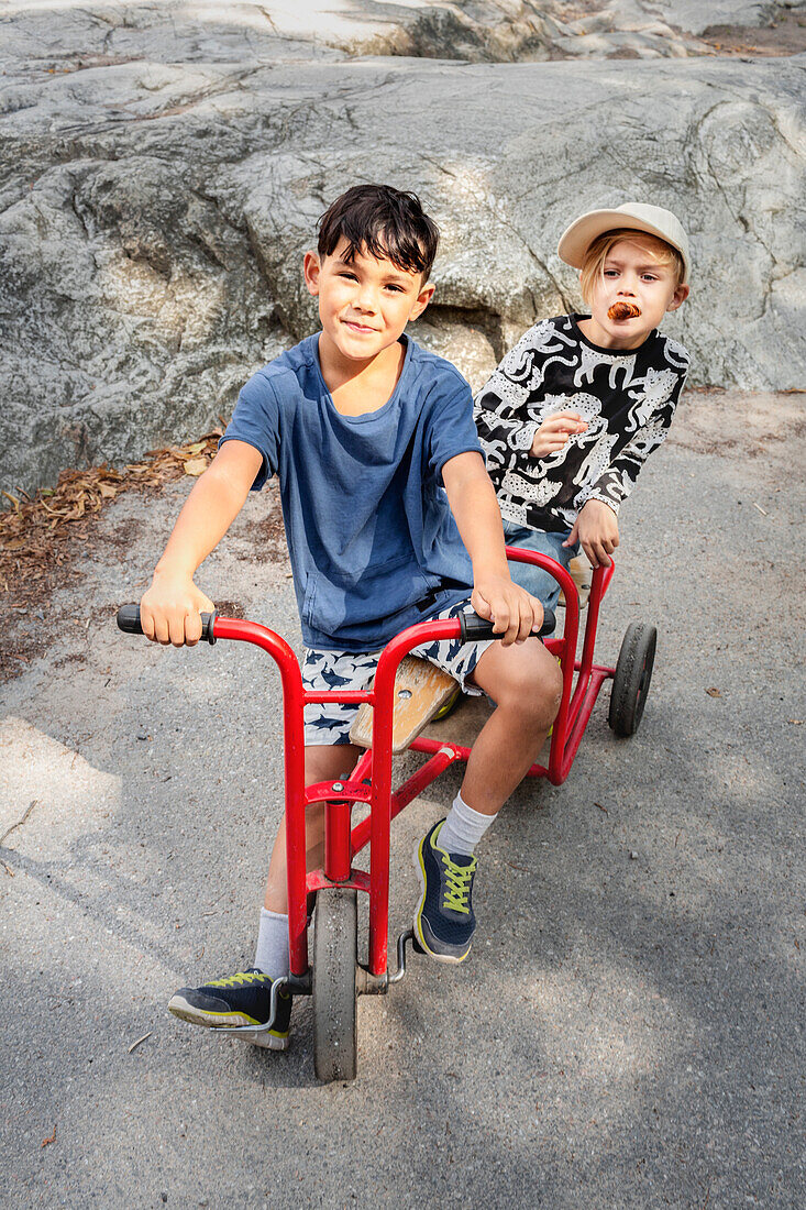 Porträt von Kinderfreunden, die Dreirad fahren