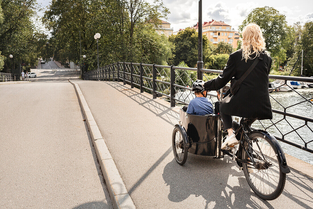 Mother riding bicycle with children in carriage