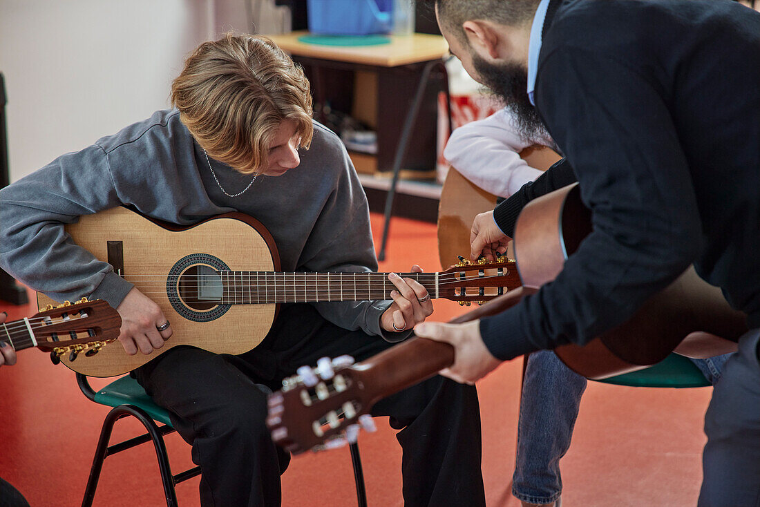 Teenagers attending guitar lesson