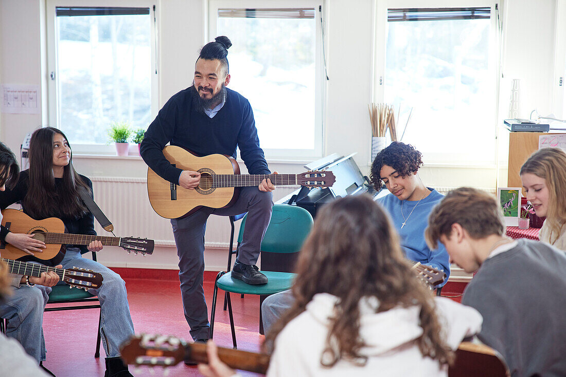 Teenagers attending guitar lesson