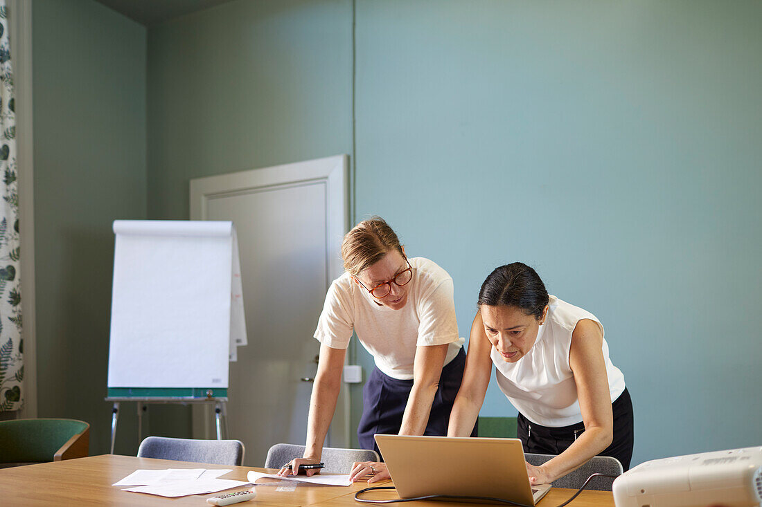 Women in boardroom using laptop