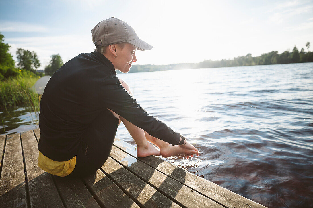 Smiling woman washing feet in lake