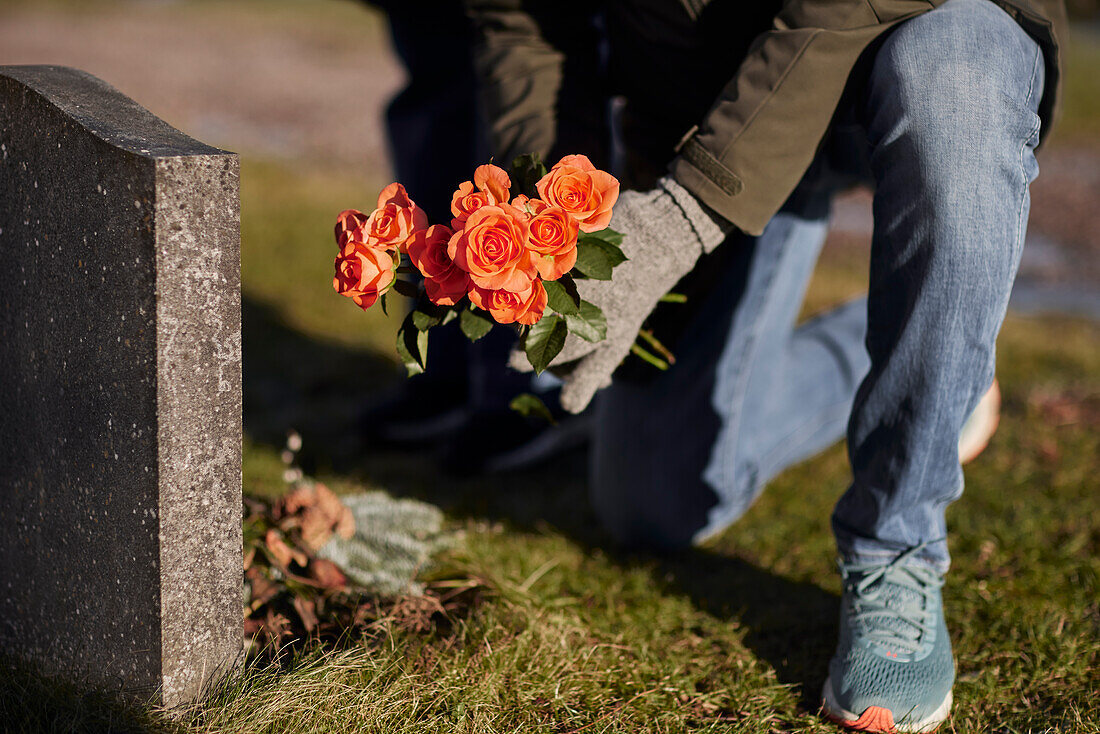 Mann mit Blumen auf dem Friedhof
