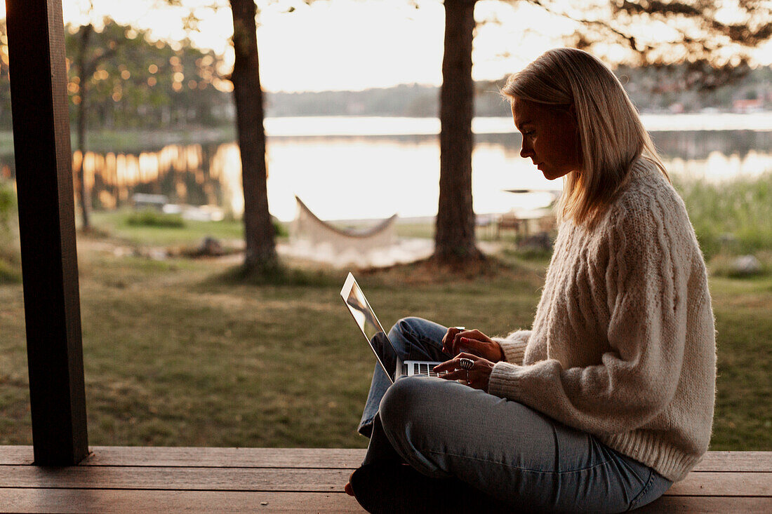 Frau mit Laptop auf der Veranda