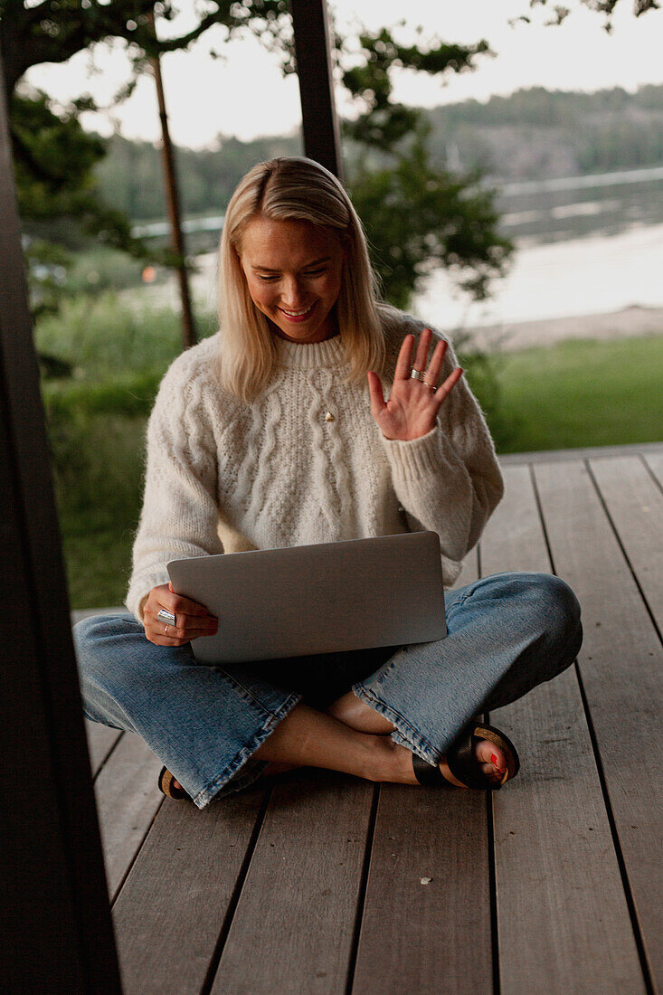 Frau mit Laptop auf der Veranda