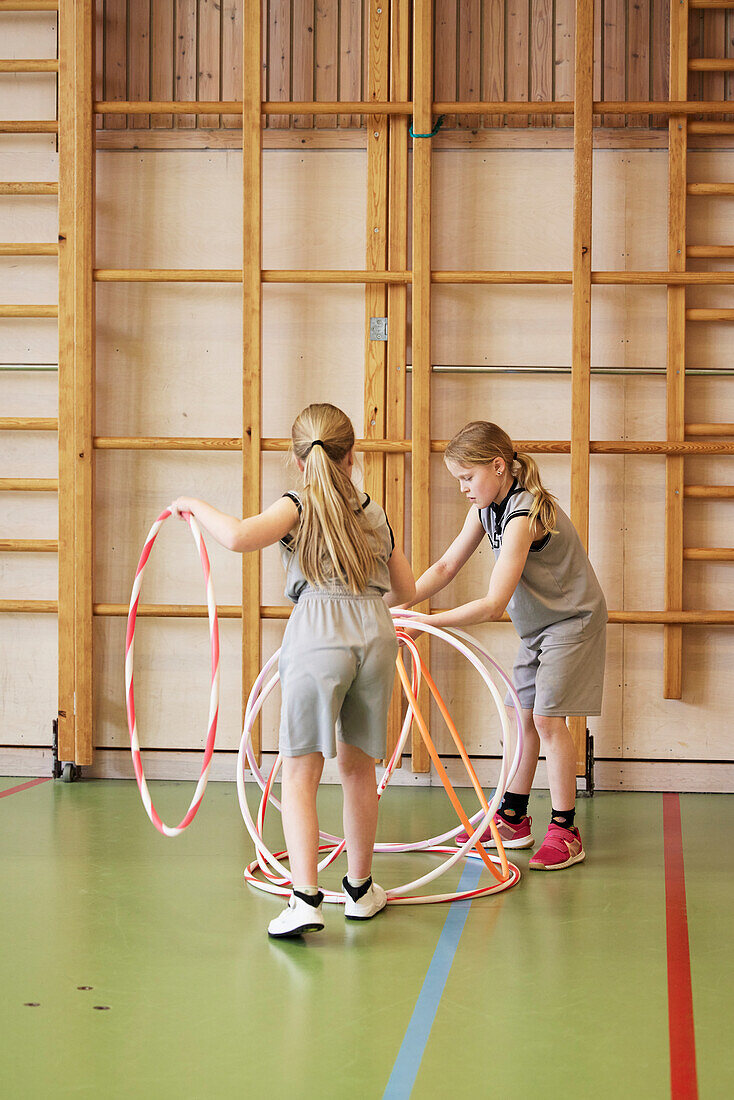 Kinder spielen mit Hula-Hoop-Reifen in der Schulturnhalle