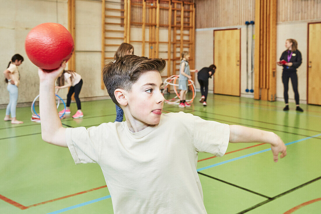 Boy throwing ball during PE class in school gym