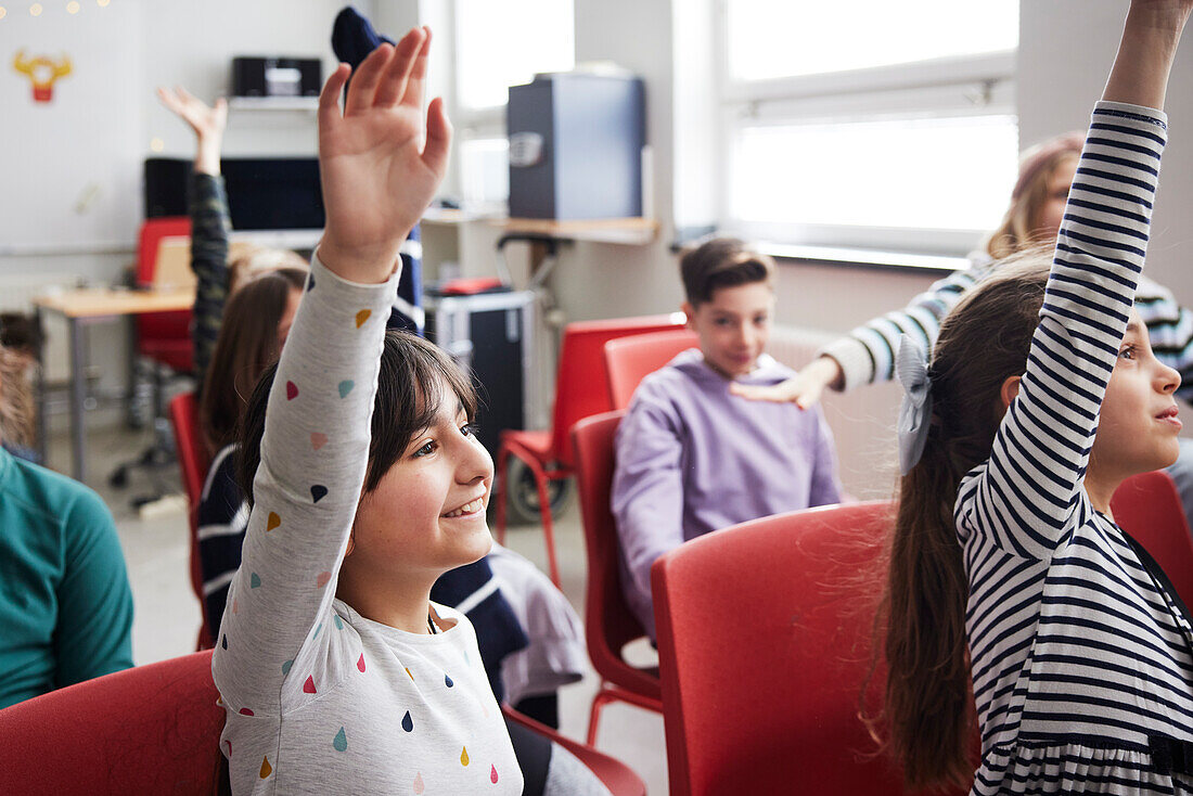 Kinder heben die Hände in der Klasse