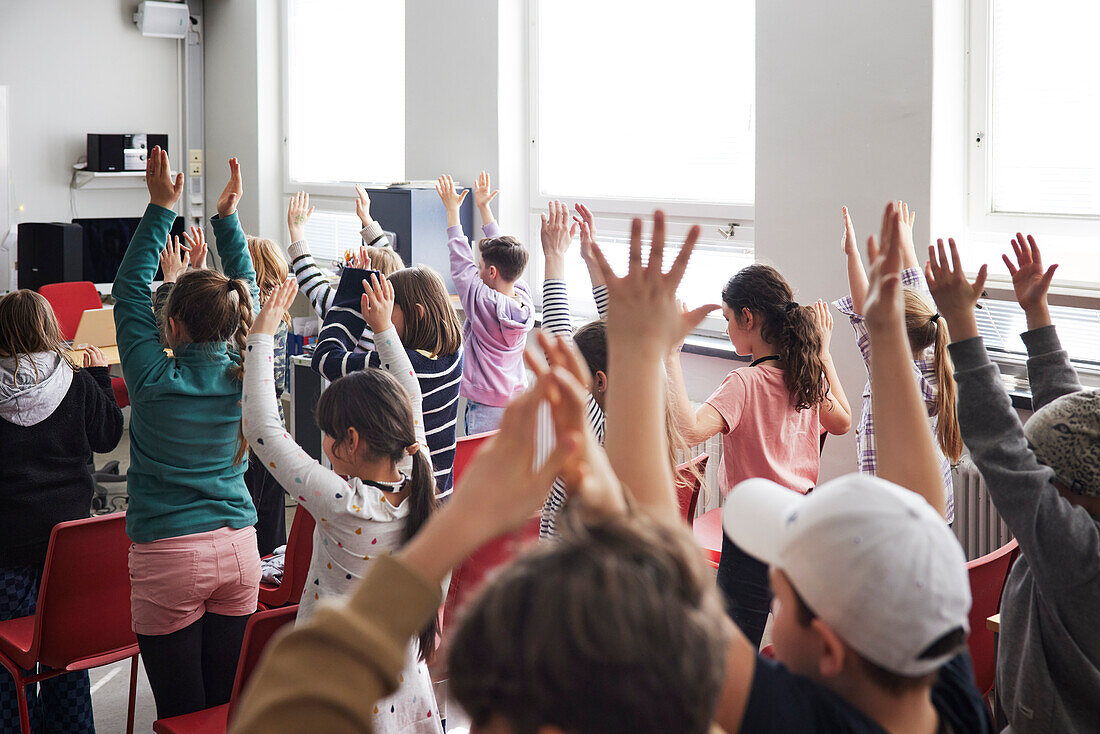 Kinder heben die Hände in der Klasse