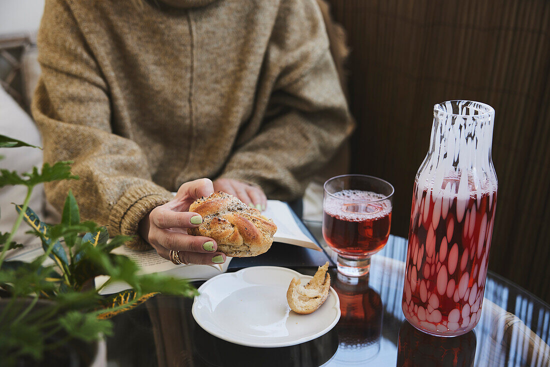 Woman reading book and eating cinnamon bun