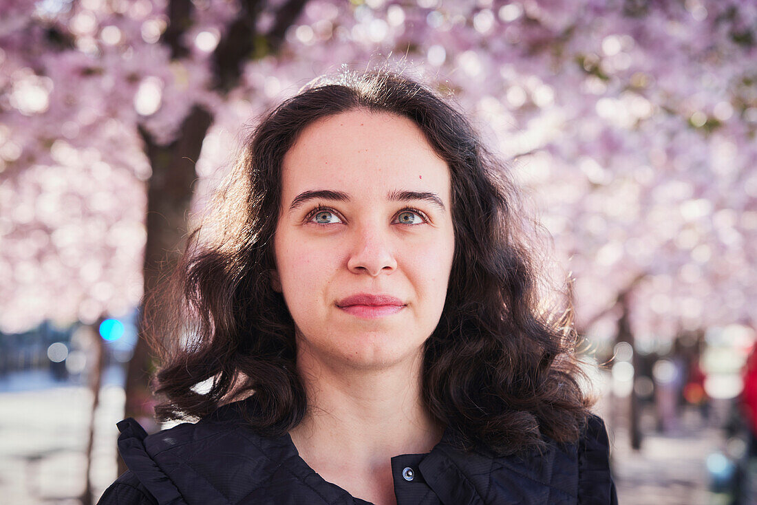 Young woman standing under cherry blossom