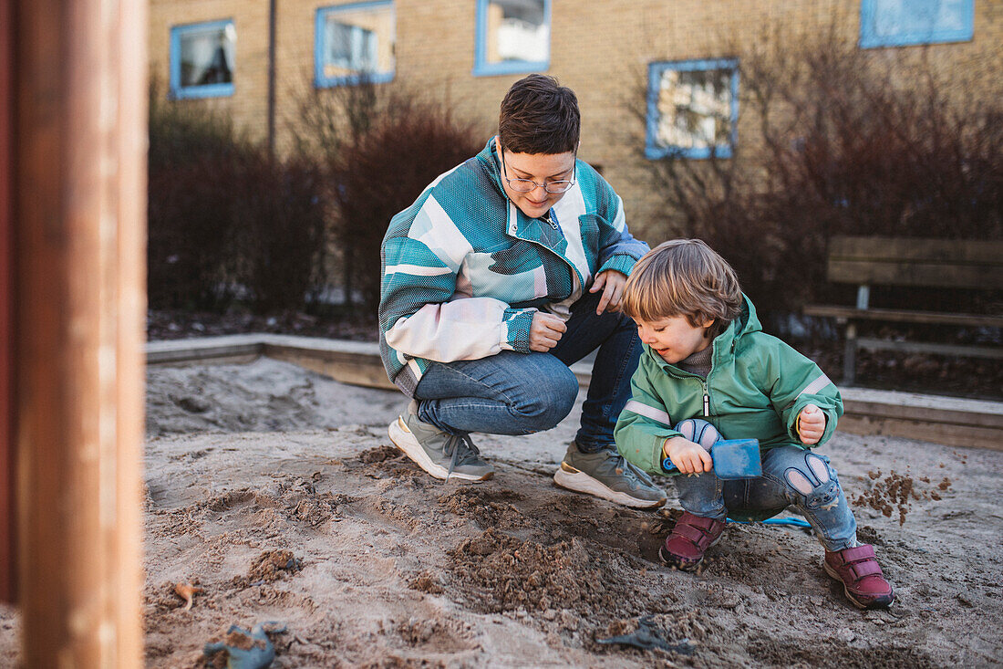 Mother playing with son in sandpit