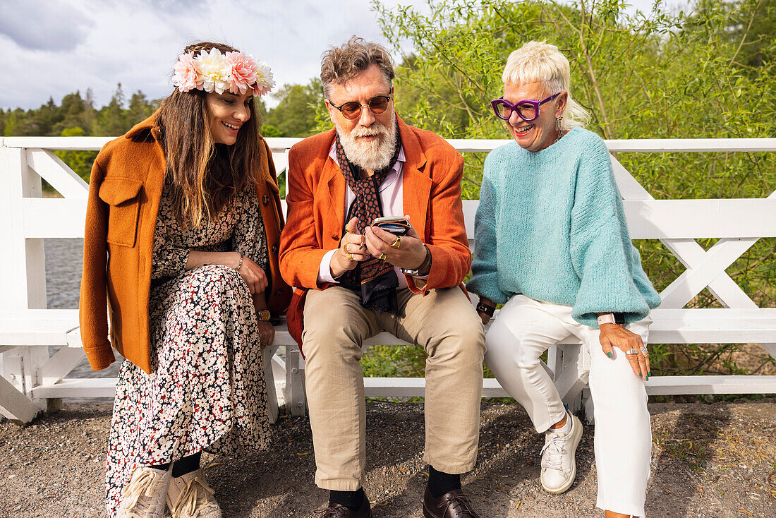 People sitting on bench and using phone