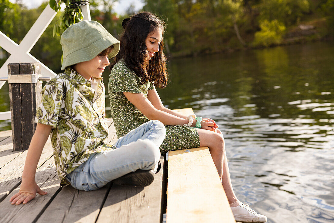 Children sitting on jetty by lake