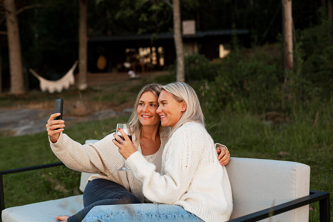 Freundinnen machen ein Selfie auf einer Bank