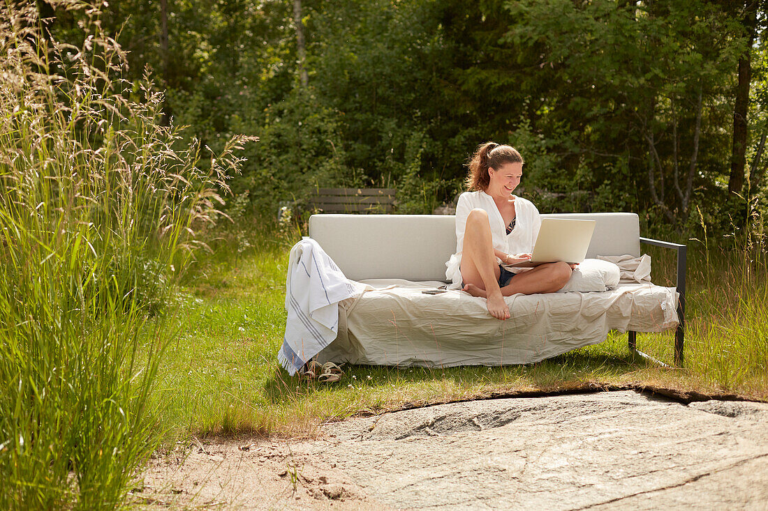 Woman using laptop on garden bench