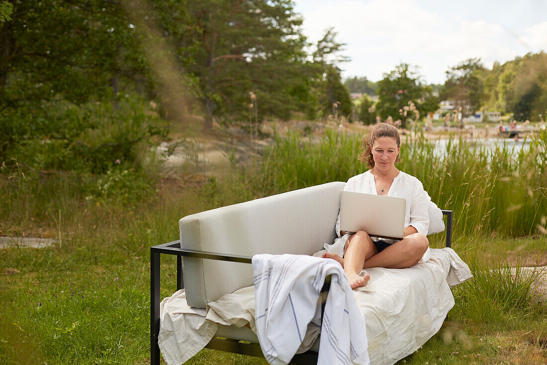 Woman using laptop on garden bench