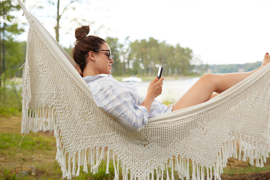 Woman using phone on hammock