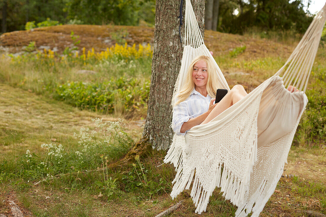 Woman using phone on hammock