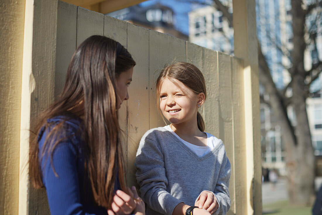 Girls standing against wooden wall