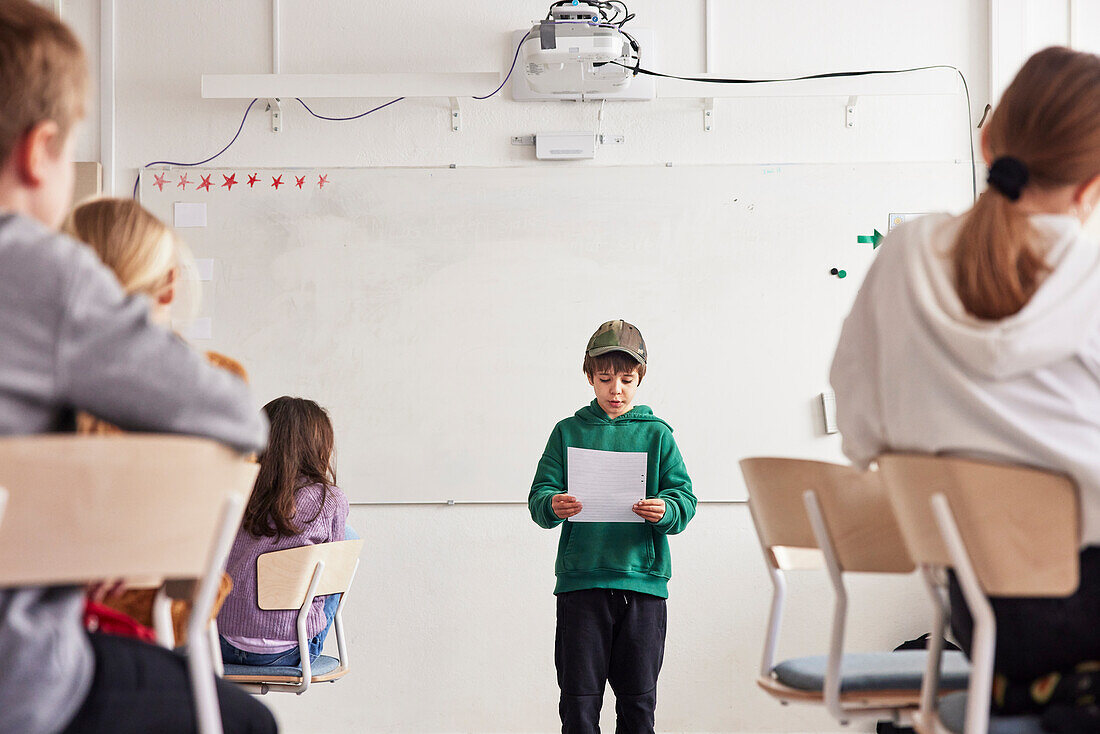 Junge liest vor der Klasse