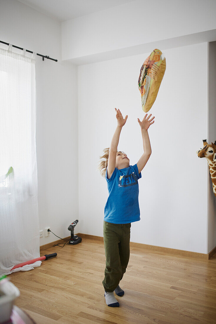 Boy throwing pillow in air