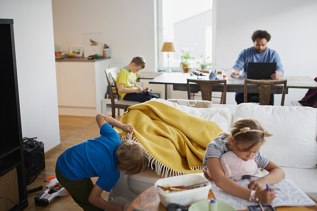 Kinder spielen, während der Vater von zu Hause aus arbeitet