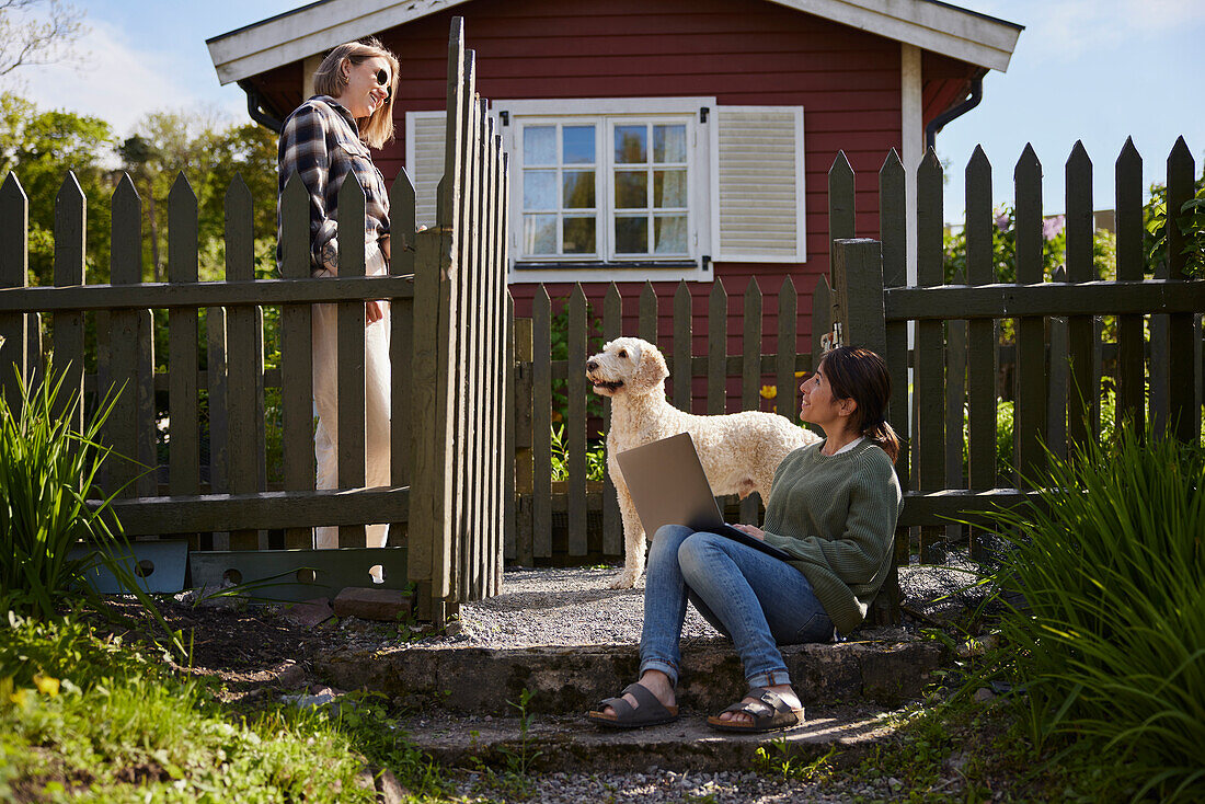 Women with laptop in front of wooden house