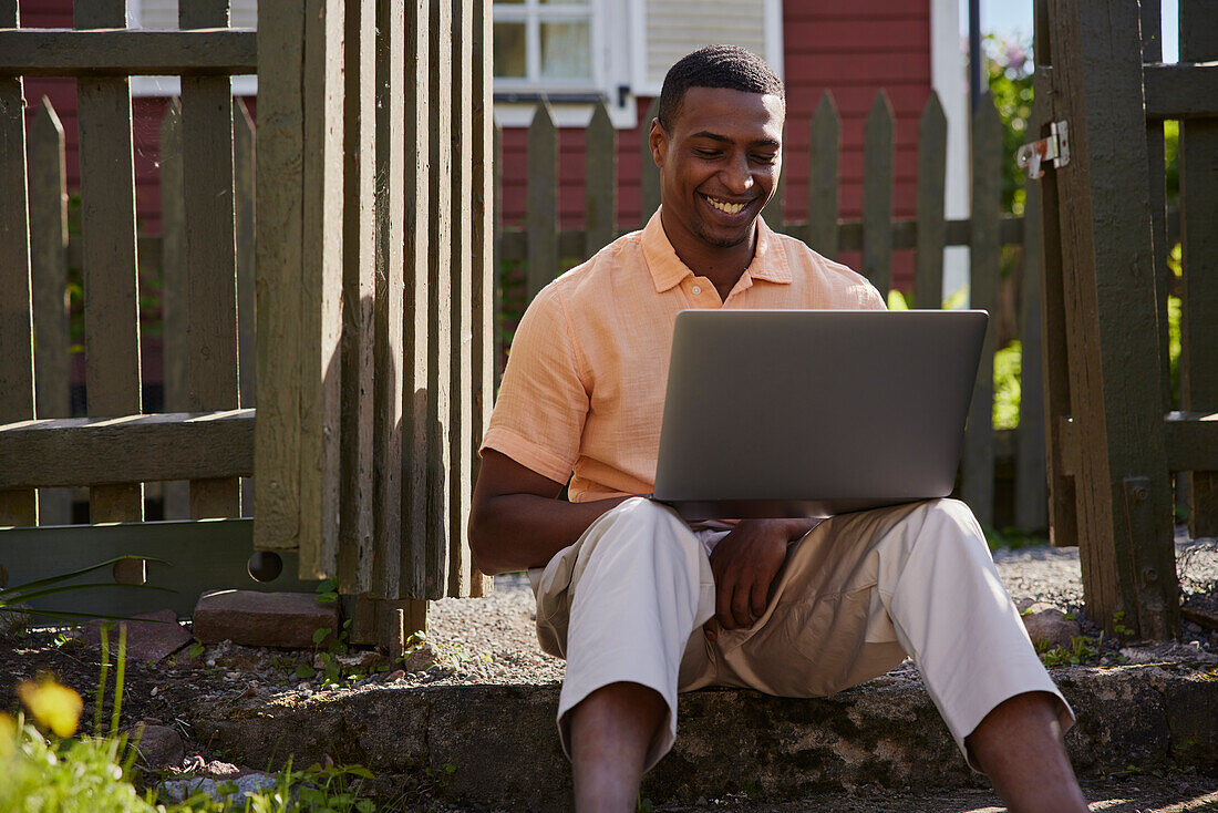 Man with laptop in front of wooden house