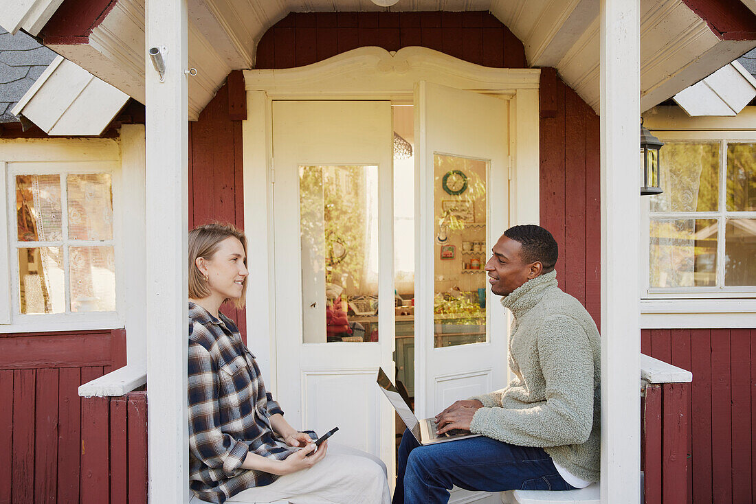 Couple sitting in front of wooden house