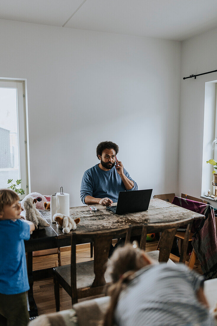 Mann arbeitet von zu Hause aus und kümmert sich um die Kinder