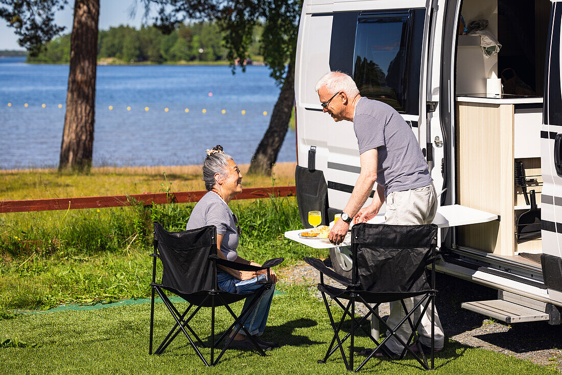 Senior couple having meal by camper van