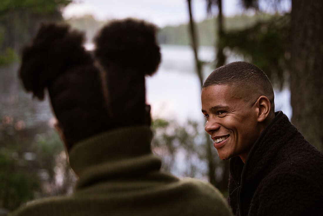 Smiling man talking to friend in forest