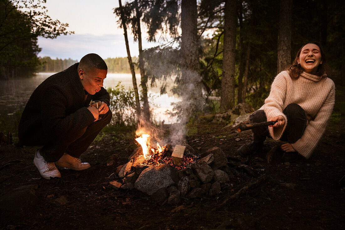 Freunde sitzen am Lagerfeuer im Wald