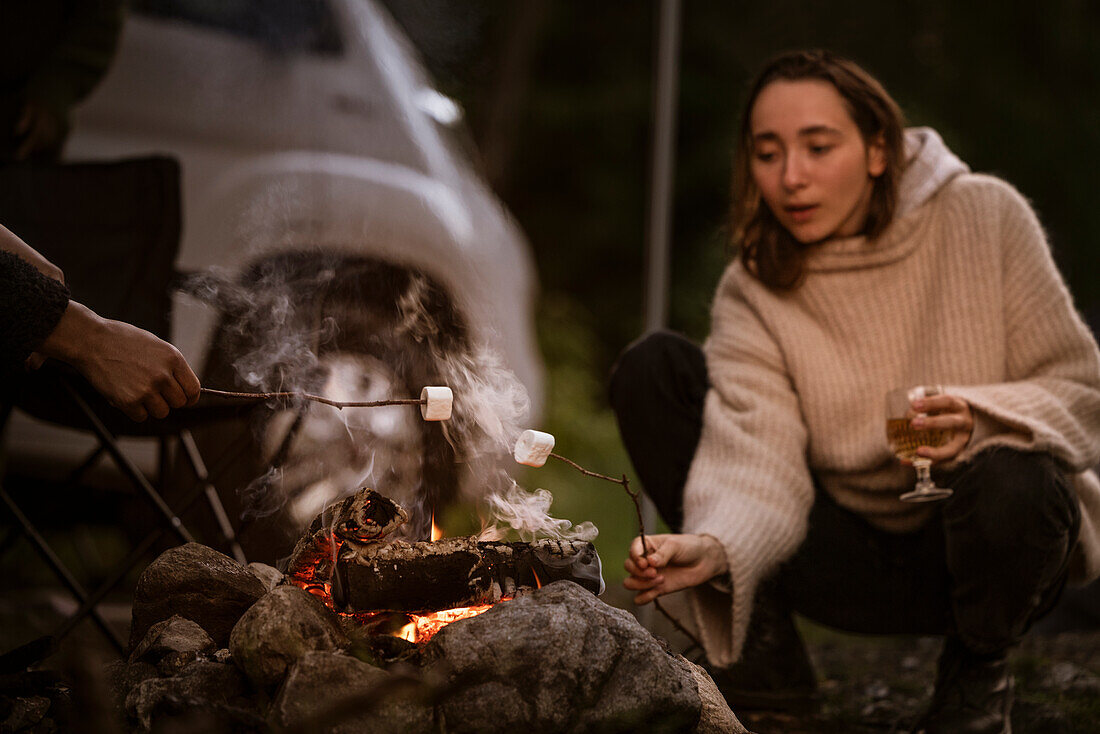 Frau röstet Marshmallow über Lagerfeuer