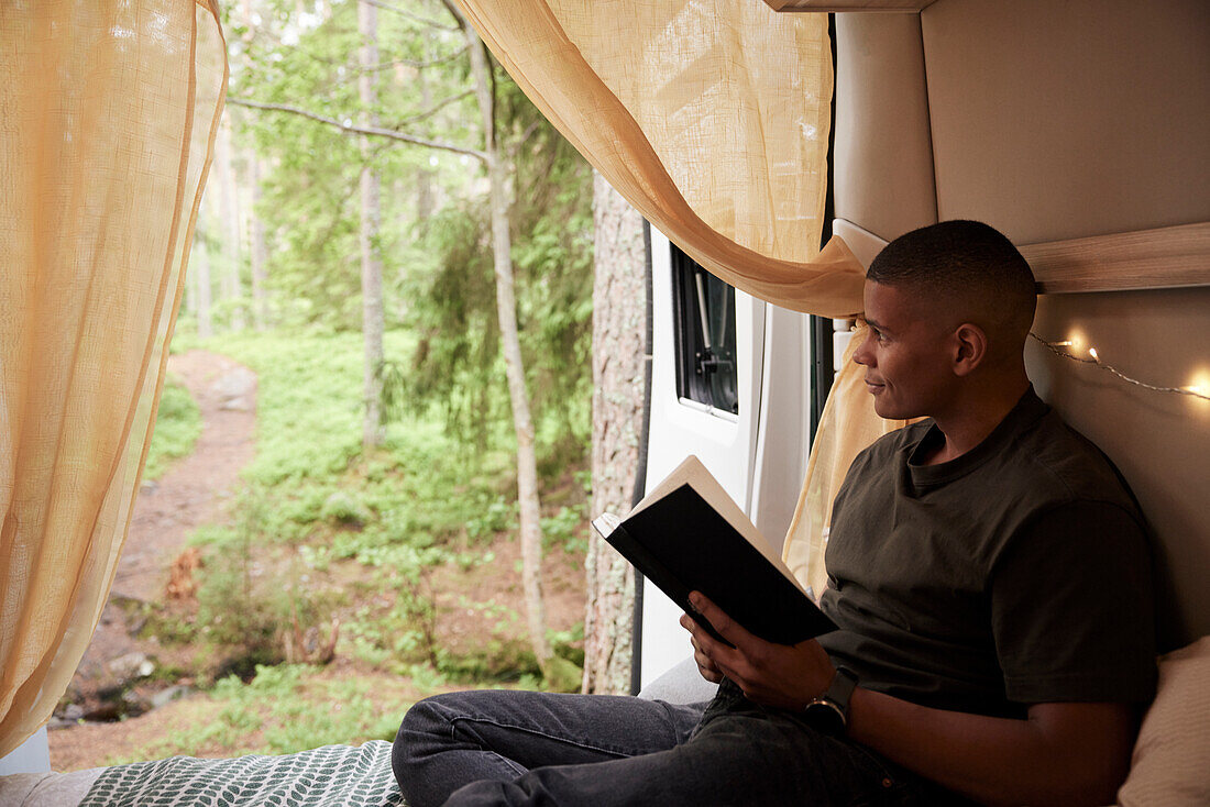 Man reading book in camper van