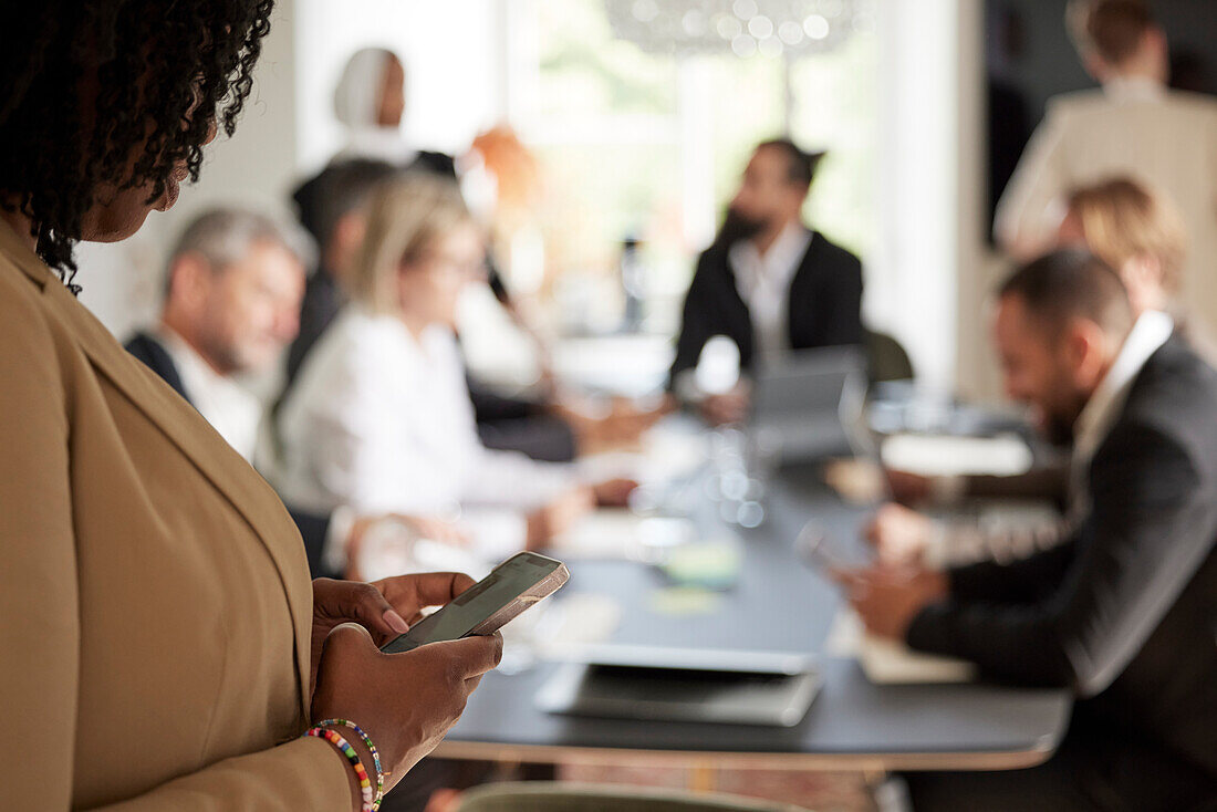 Woman using cell phone during business meeting