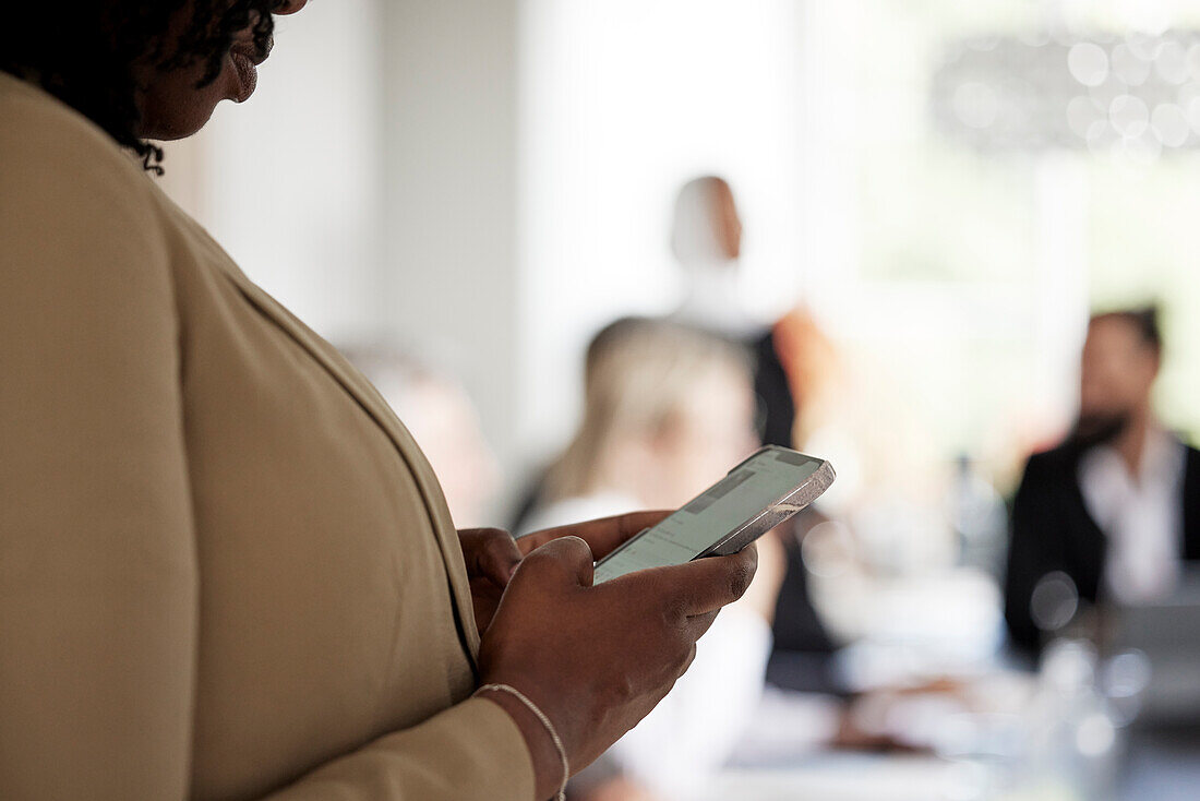 Woman using cell phone during business meeting